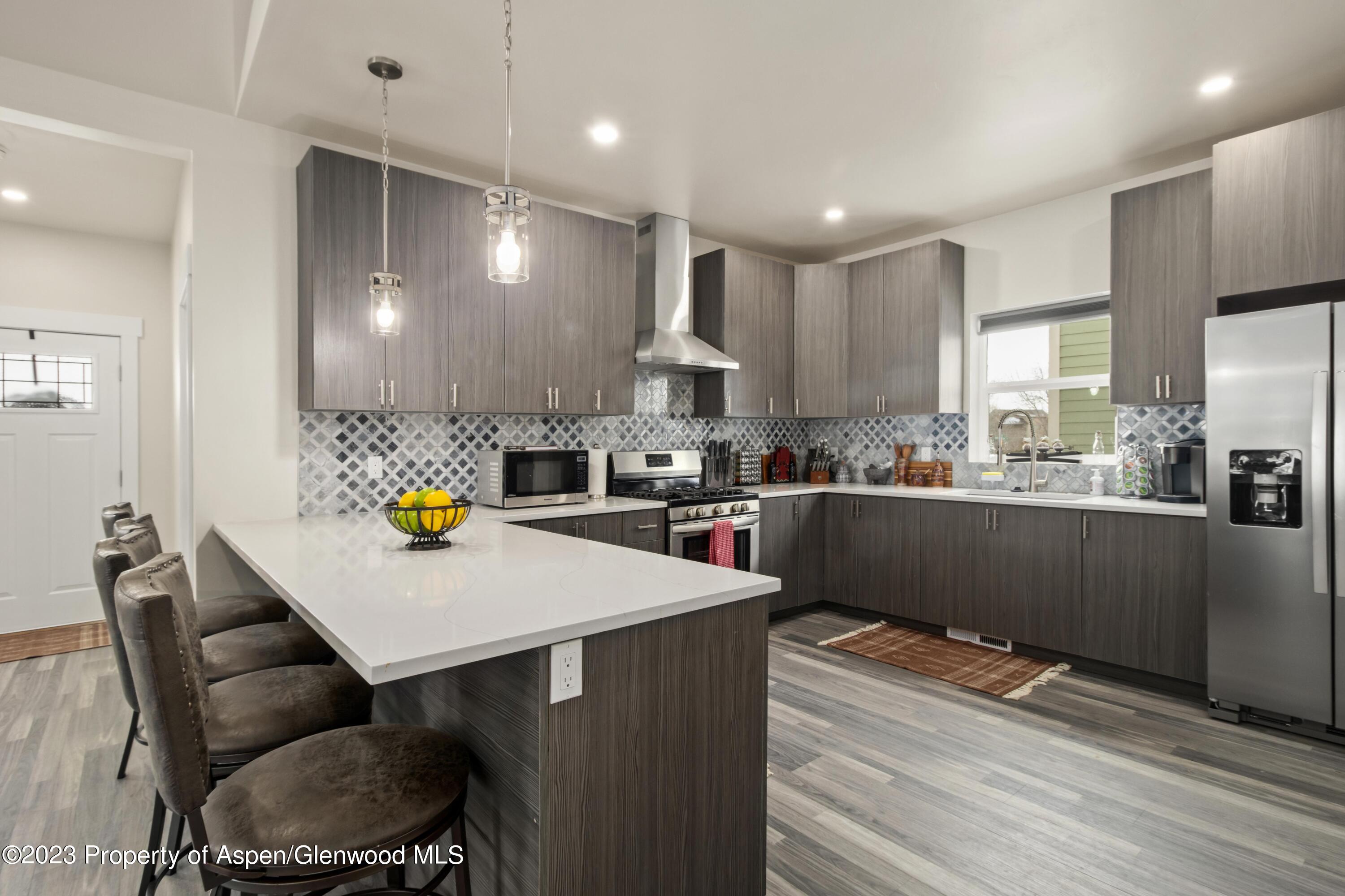 1089 Bedrock Circle Silt, CO 81652 - Photo 5 of 16 a kitchen with stainless steel appliances a sink a stove a refrigerator cabinets and a dining table with wooden floor
