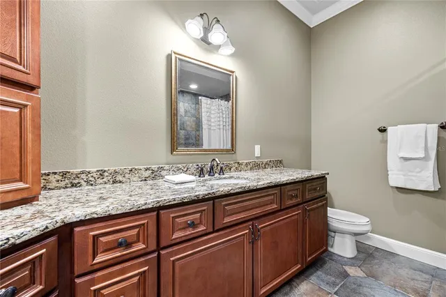 a bathroom with a granite countertop sink a toilet and mirror
