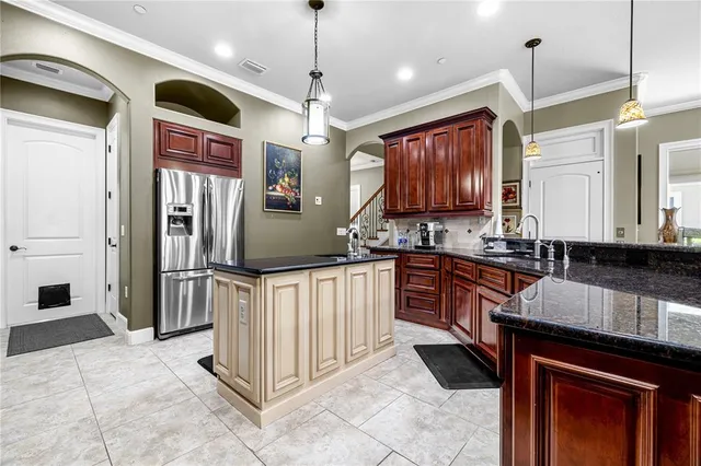 a kitchen with stainless steel appliances granite countertop a refrigerator a sink dishwasher a oven a dining table and chairs with wooden floor