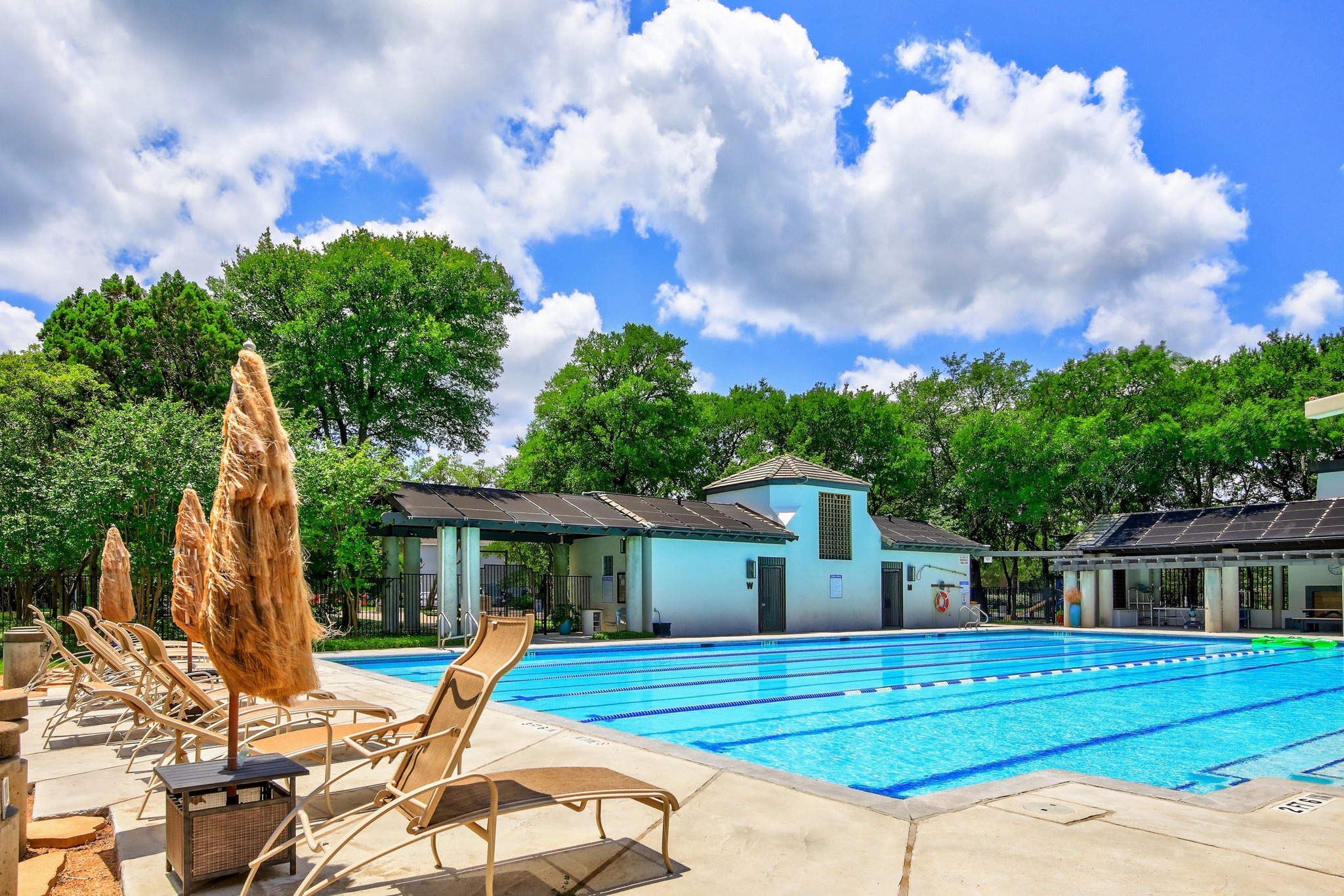 7705 Jester Boulevard Austin, TX 78730 - Photo 31 of 36 A refreshing outdoor pool awaits, flanked by lounge chairs and lush greenery under a bright sky.