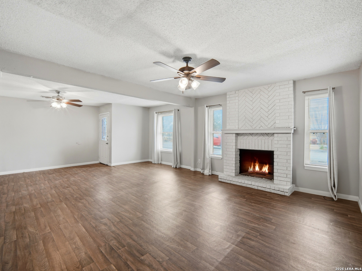 an empty room with windows a fireplace