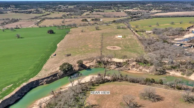 an aerial view of a house with a yard and lake view in back