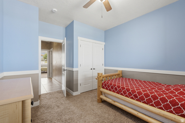 2567 West Rim Rock Drive Stockton, UT 84071 - Photo 32 of 64 Carpeted room with a two-tone wall treatment, featuring a ceiling fan with light fixture and a built-in closet with double doors
