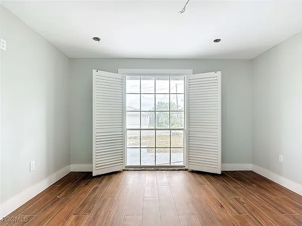 an empty room with wooden floor and window
