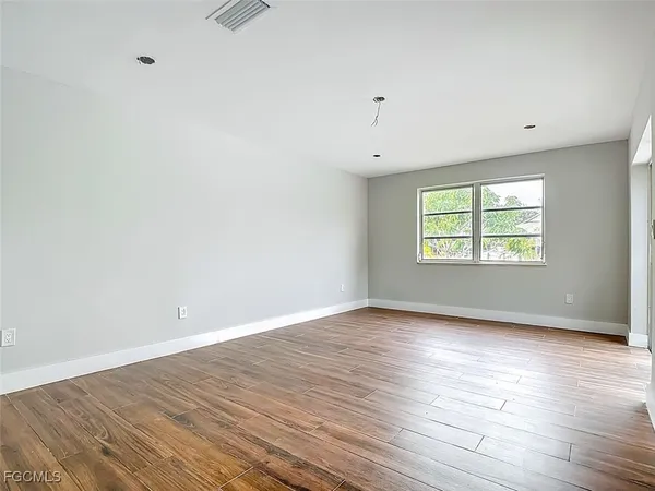 an empty room with wooden floor and windows