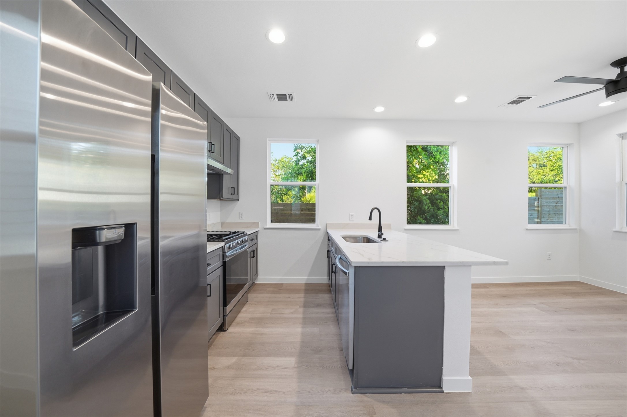 2212 Yellow Jacket Lane, Unit 2 Austin, TX 78741 - Photo 8 of 25 Modern kitchen featuring stainless steel appliances, dark gray cabinetry, white countertops, and a central island with an integrated sink and matte black faucet