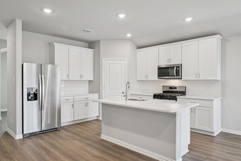 a kitchen with white cabinets stainless steel appliances and wooden floor