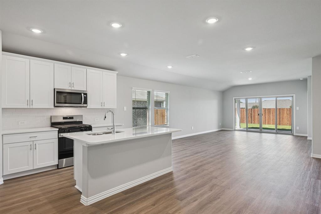 2112 Rannoch Street Sherman, TX 75092 - Photo 3 of 32 a large kitchen with stainless steel appliances granite countertop a stove a sink dishwasher a microwave oven with cabinets and wooden floor