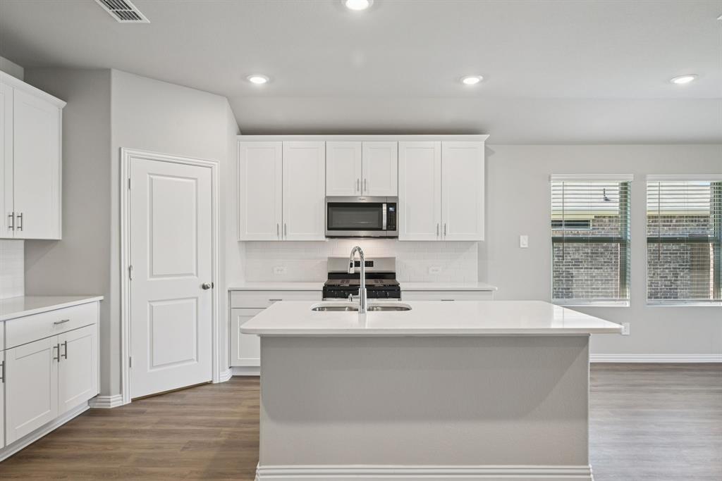2112 Rannoch Street Sherman, TX 75092 - Photo 4 of 32 a kitchen with kitchen island white cabinets and stainless steel appliances