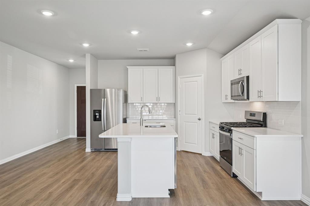 2112 Rannoch Street Sherman, TX 75092 - Photo 5 of 32 a kitchen with stainless steel appliances a refrigerator stove oven and white cabinets with wooden floor
