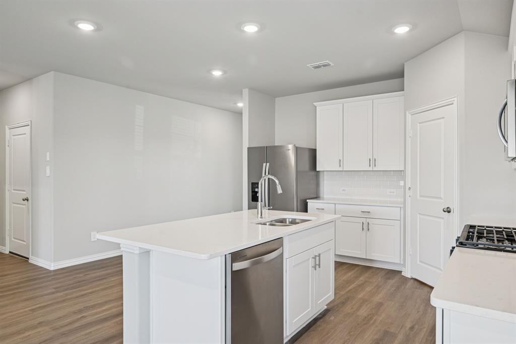 2112 Rannoch Street Sherman, TX 75092 - Photo 6 of 32 a kitchen with a sink a stove a refrigerator and white cabinets