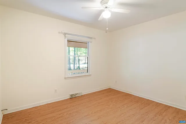 an empty room with a window and a fan