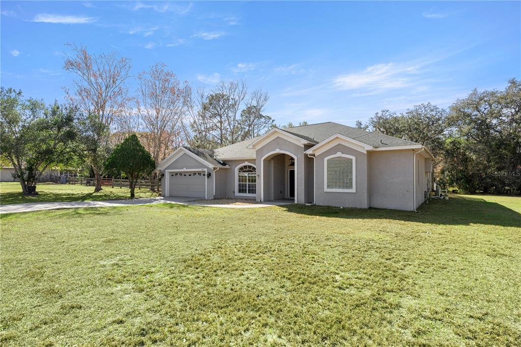 3030 South Bay Berry Point Inverness, FL 34450 - Photo 2 of 48 a view of a white house with a yard and a large tree