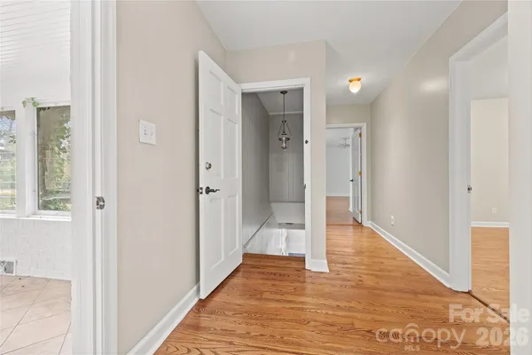 a view of a hallway with wooden floor and a bathroom