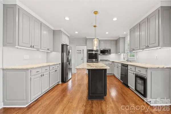 a kitchen with granite countertop a sink cabinets and stainless steel appliances