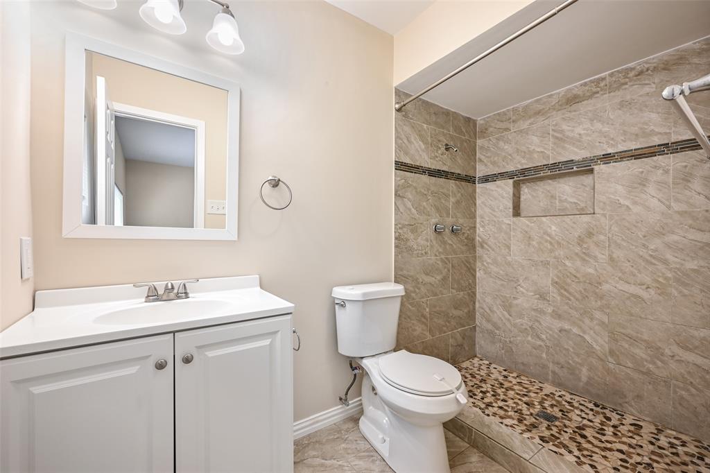 7318 Emory Oak Lane Dallas, TX 75249 - Photo 17 of 28 Full bathroom featuring a white vanity with integrated sink, framed mirror, and two-light fixture
