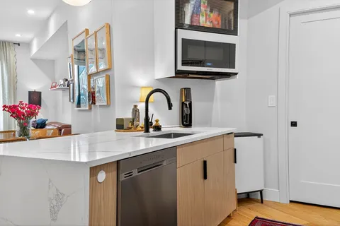 a kitchen with a sink cabinets and a flat screen tv