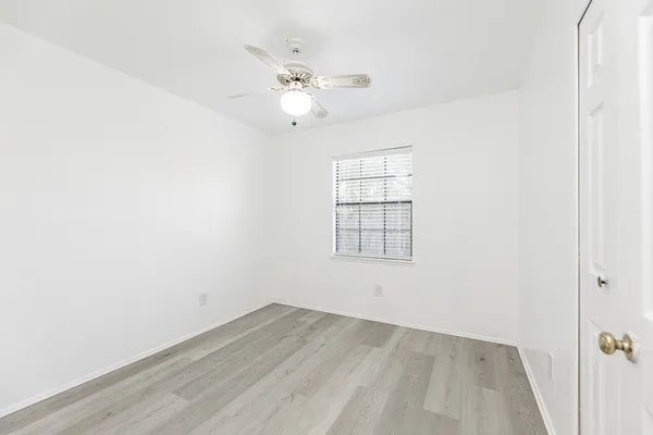 an empty room with a window and ceiling fan
