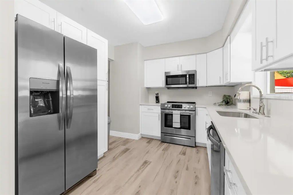 8215 Quail Road Seminole, FL 33777 - Photo 4 of 25 a kitchen with a refrigerator stove and microwave