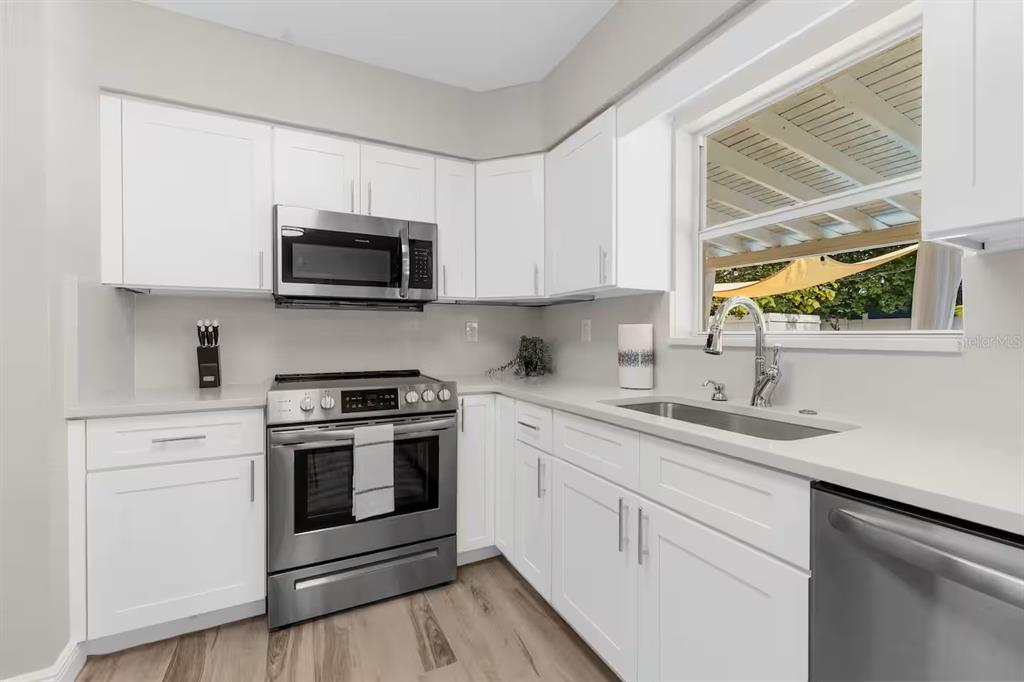 8215 Quail Road Seminole, FL 33777 - Photo 5 of 25 a kitchen with stainless steel appliances granite countertop a sink a stove and microwave with wooden floor