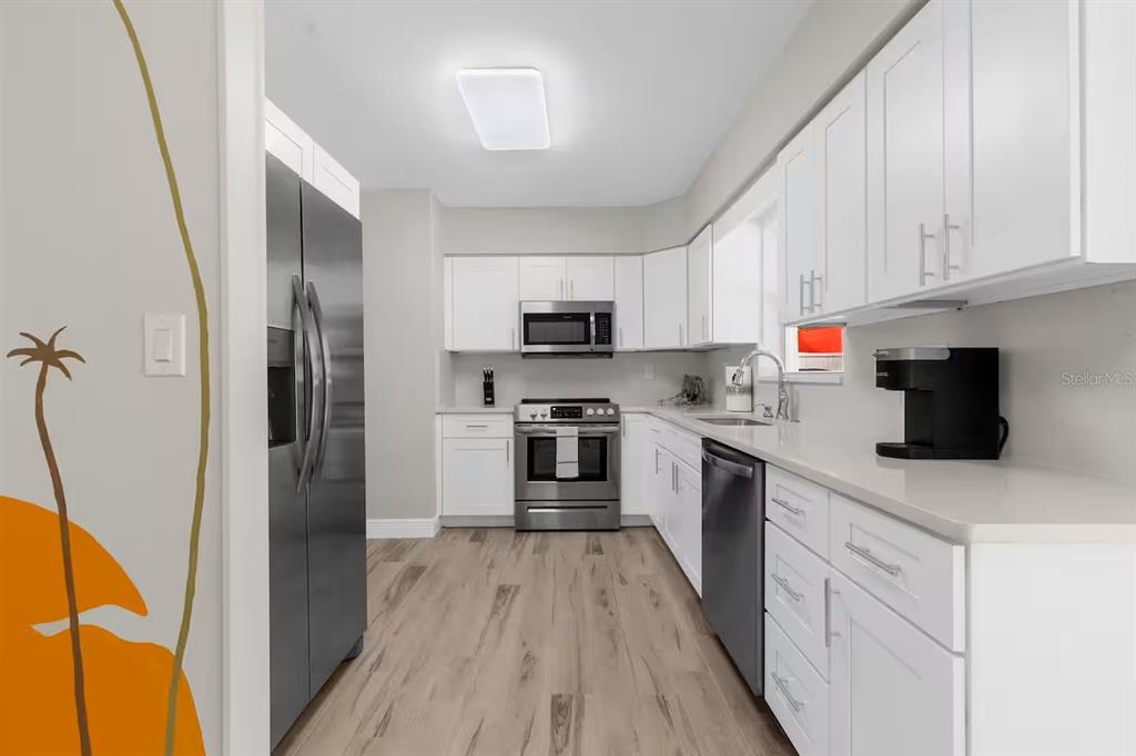 8215 Quail Road Seminole, FL 33777 - Photo 7 of 25 a kitchen with cabinets and stainless steel appliances