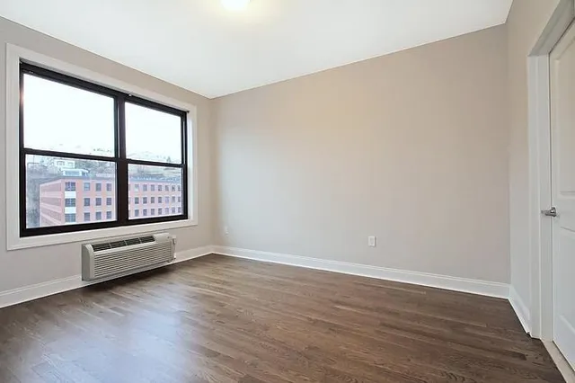 a view of an empty room with window and wooden floor