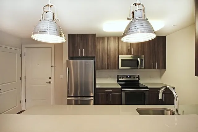 a kitchen with stainless steel appliances a sink a refrigerator and cabinets