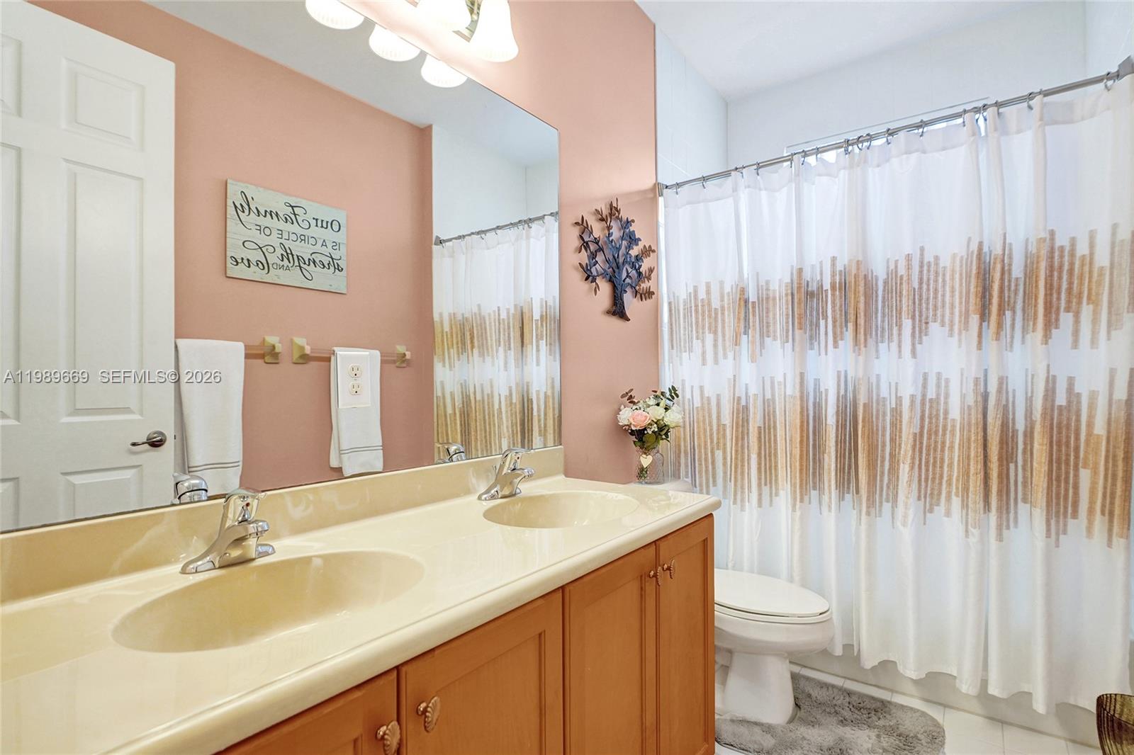 17713 Southwest 47th Street Miramar, FL 33029 - Photo 61 of 94 a bathroom with a sink a toilet and shower curtain