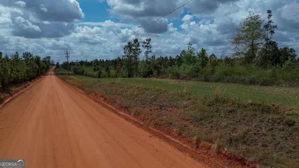 a view of dirt field with trees in the background