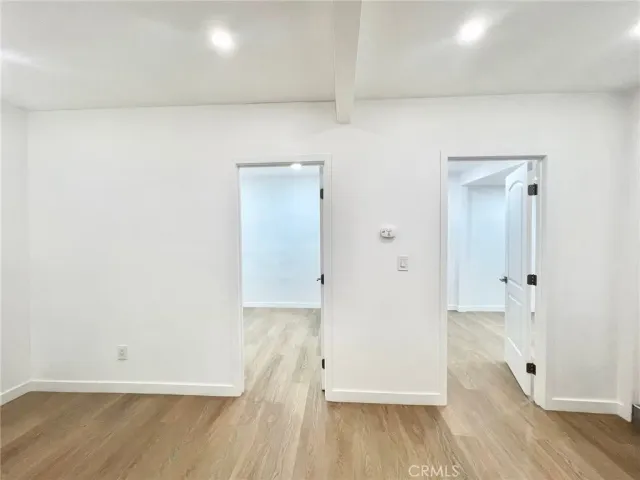 an empty room with wooden floor and entrance