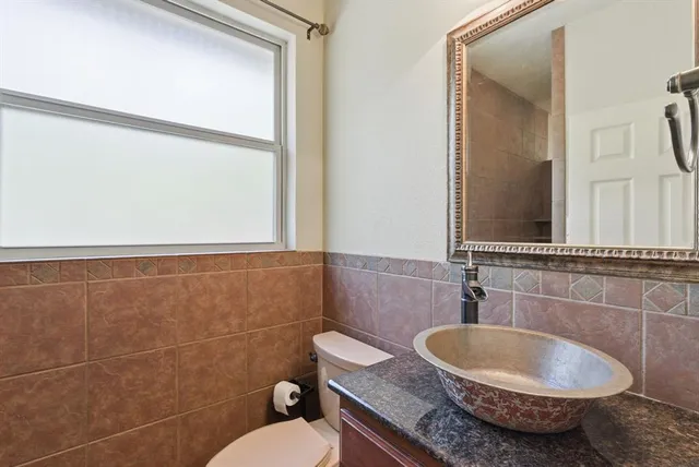a bathroom with a granite countertop toilet a sink and a mirror