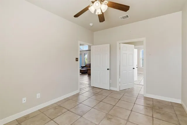 an empty room with closet and a chandelier fan