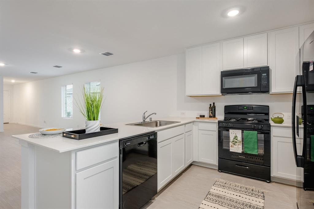 1119 Barbary Flds Street Forney, TX 75126 - Photo 5 of 14 a kitchen with stainless steel appliances kitchen island granite countertop a sink a stove cabinets and a refrigerator