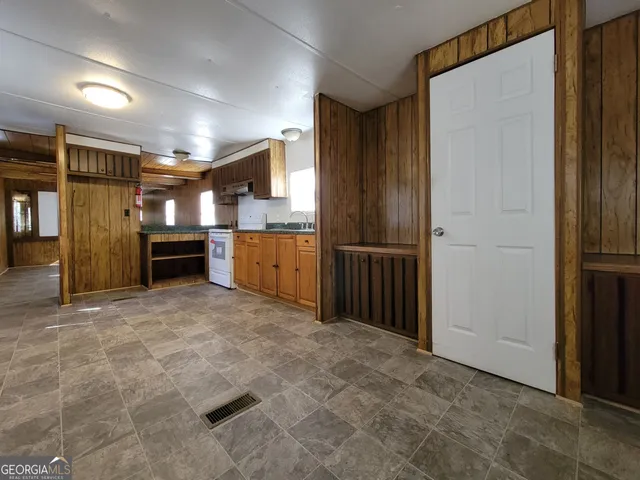 a view of kitchen with refrigerator and wooden cabinets