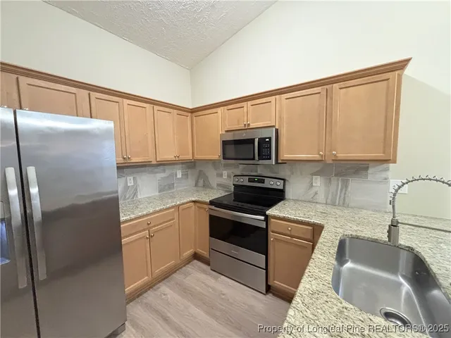 a kitchen with granite countertop a sink a stove and refrigerator