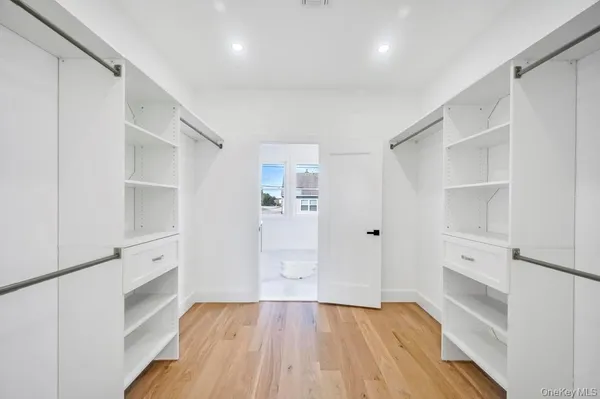 a view of an empty walk in closet with wooden floor