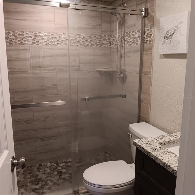 4158 Tamiami Trail, Unit R8 Port Charlotte, FL 33952 - Photo 16 of 29 a bathroom with a granite countertop toilet and a shower