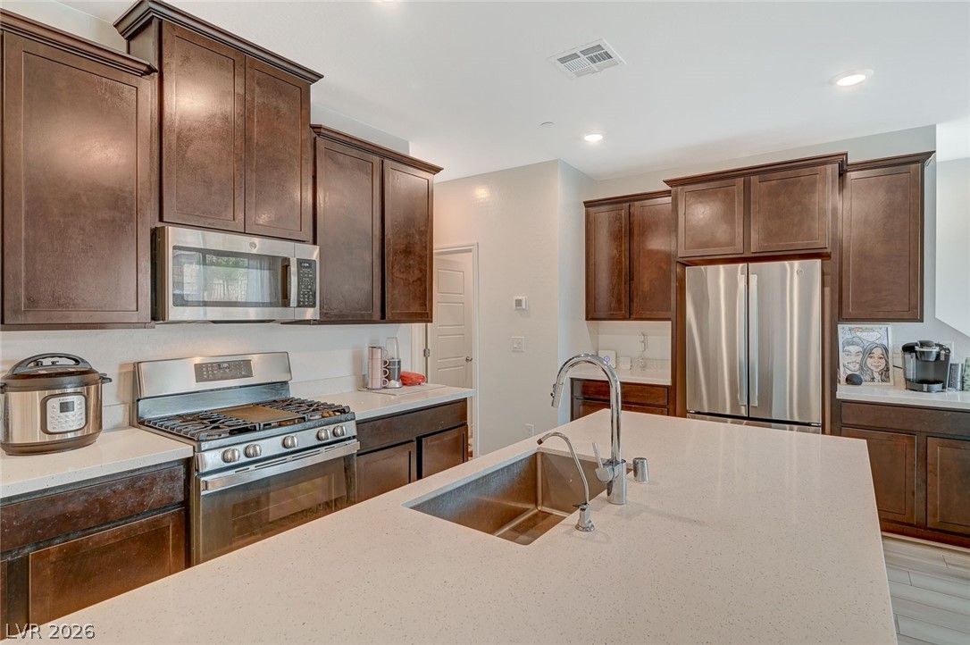 8855 Roadrunner Ravine Street Las Vegas, NV 89166 - Photo 14 of 54 Kitchen featuring stainless steel appliances, recessed lighting, visible vents, a sink, and dark brown cabinetry