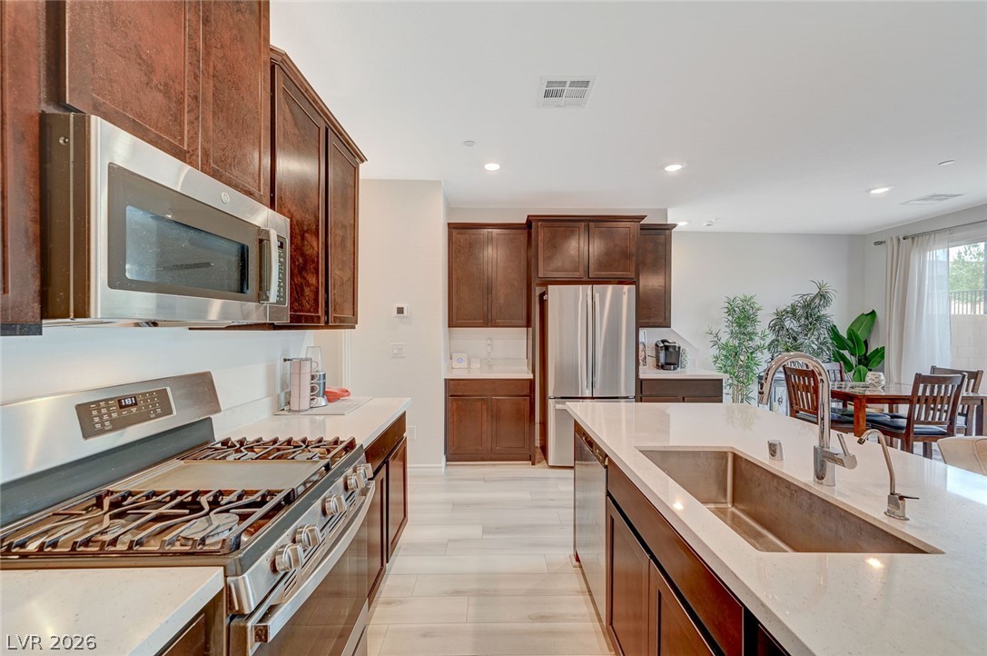 8855 Roadrunner Ravine Street Las Vegas, NV 89166 - Photo 16 of 54 Kitchen featuring recessed lighting, stainless steel appliances, a sink, visible vents, and light stone countertops