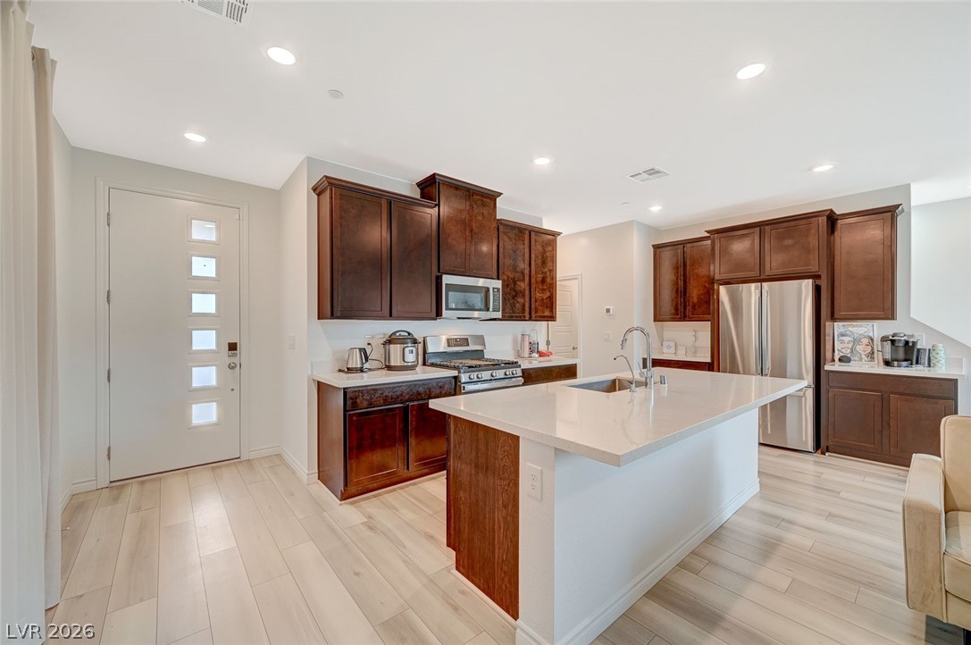 8855 Roadrunner Ravine Street Las Vegas, NV 89166 - Photo 17 of 54 Kitchen featuring visible vents, appliances with stainless steel finishes, a sink, and light wood-style flooring