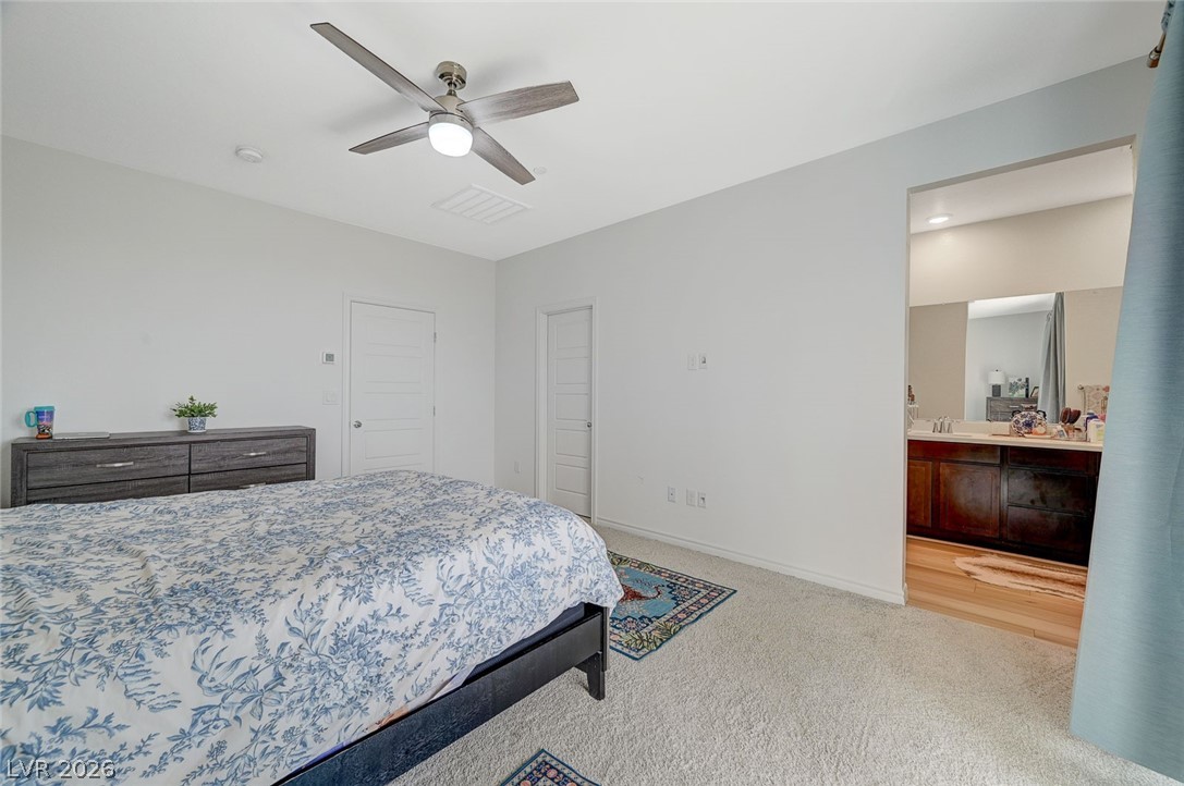 8855 Roadrunner Ravine Street Las Vegas, NV 89166 - Photo 27 of 54 Bedroom with carpet floors, visible vents, ceiling fan, ensuite bath, and baseboards
