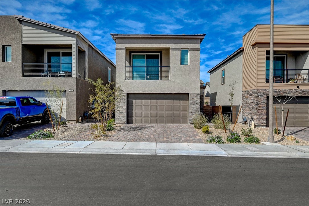 8855 Roadrunner Ravine Street Las Vegas, NV 89166 - Photo 3 of 54 Contemporary house featuring an attached garage, stone siding, decorative driveway, and stucco siding