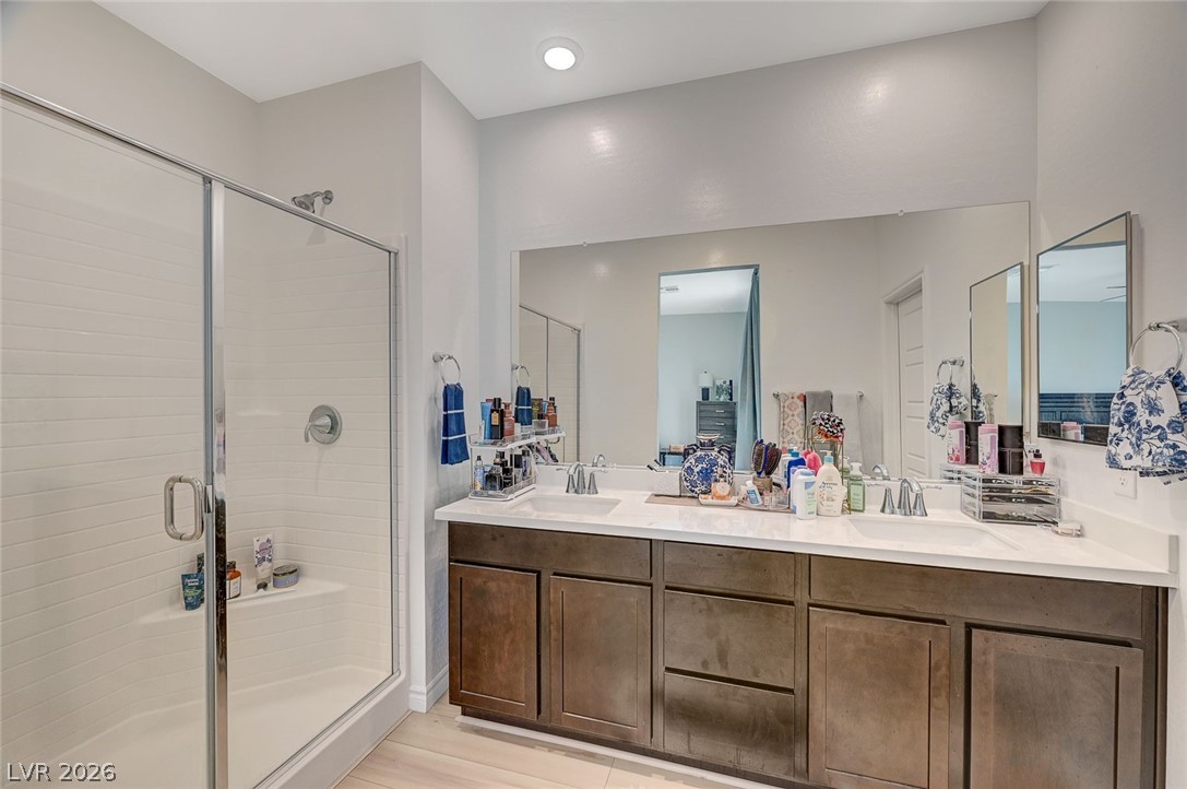 8855 Roadrunner Ravine Street Las Vegas, NV 89166 - Photo 34 of 54 Bathroom featuring a stall shower, wood finished floors, a sink, and double vanity