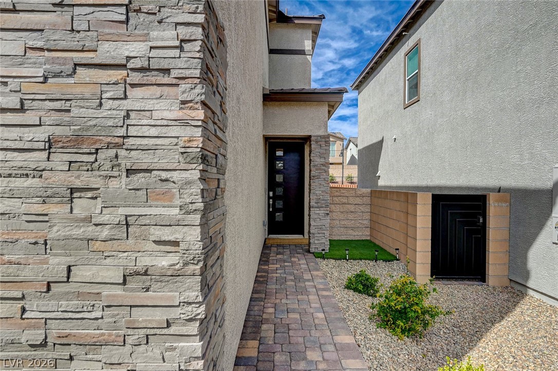 8855 Roadrunner Ravine Street Las Vegas, NV 89166 - Photo 5 of 54 View of exterior entry featuring stone siding and stucco siding