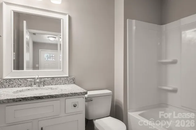 a bathroom with a granite countertop sink a mirror and a toilet