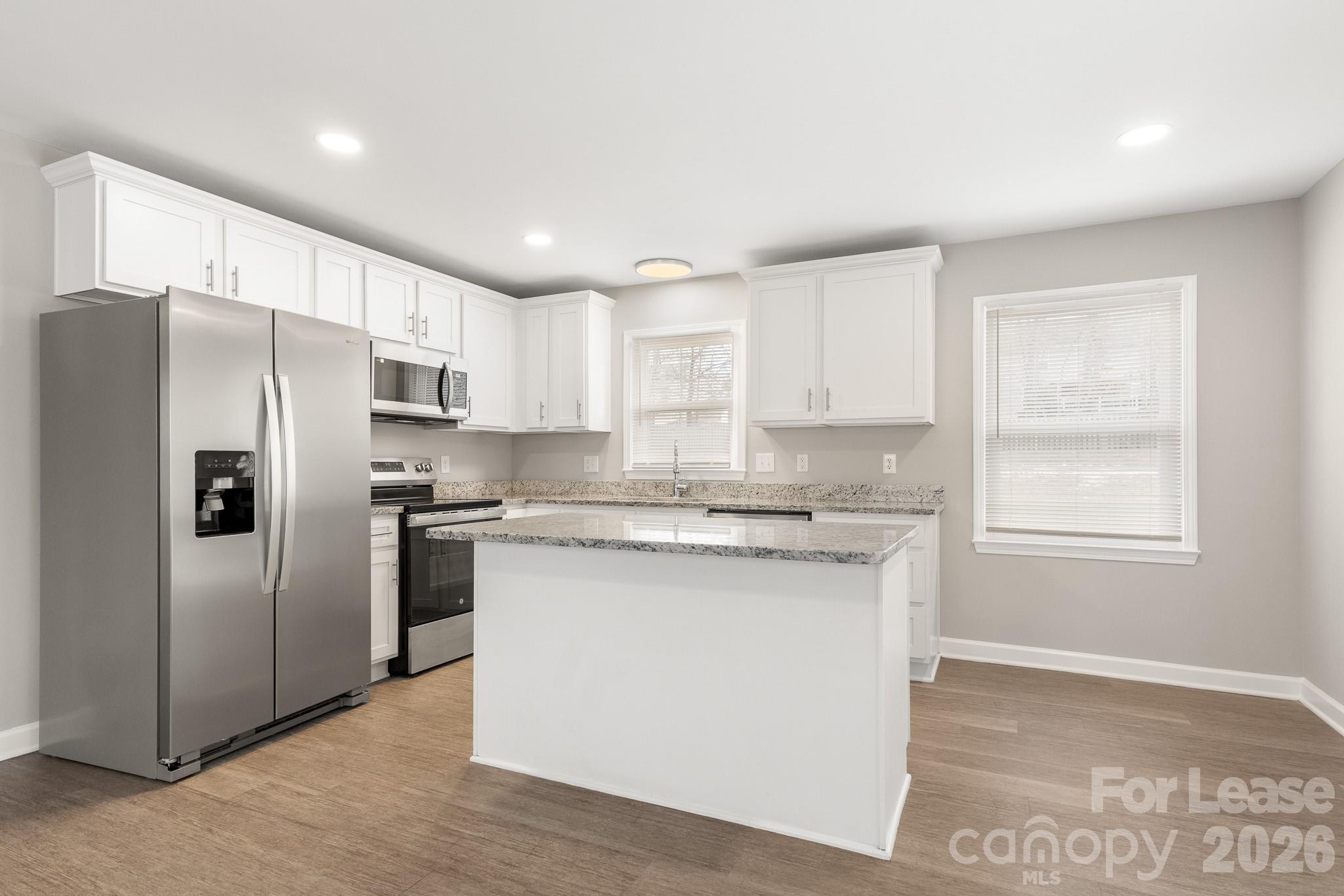 11805 Harrisburg Road Indian Land, SC 29707 - Photo 10 of 47 a kitchen with stainless steel appliances granite countertop a refrigerator a sink dishwasher a stove and white countertops with wooden floor