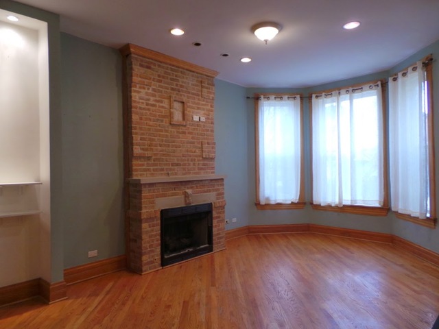 1231 North Artesian Avenue, Unit 2 Chicago, IL 60622 - Photo 2 of 9 an empty room with wooden floor and fireplace