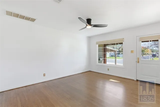 an empty room with wooden floor and windows