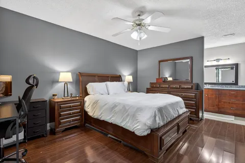 a spacious bedroom with a bed a chandelier and flat screen tv
