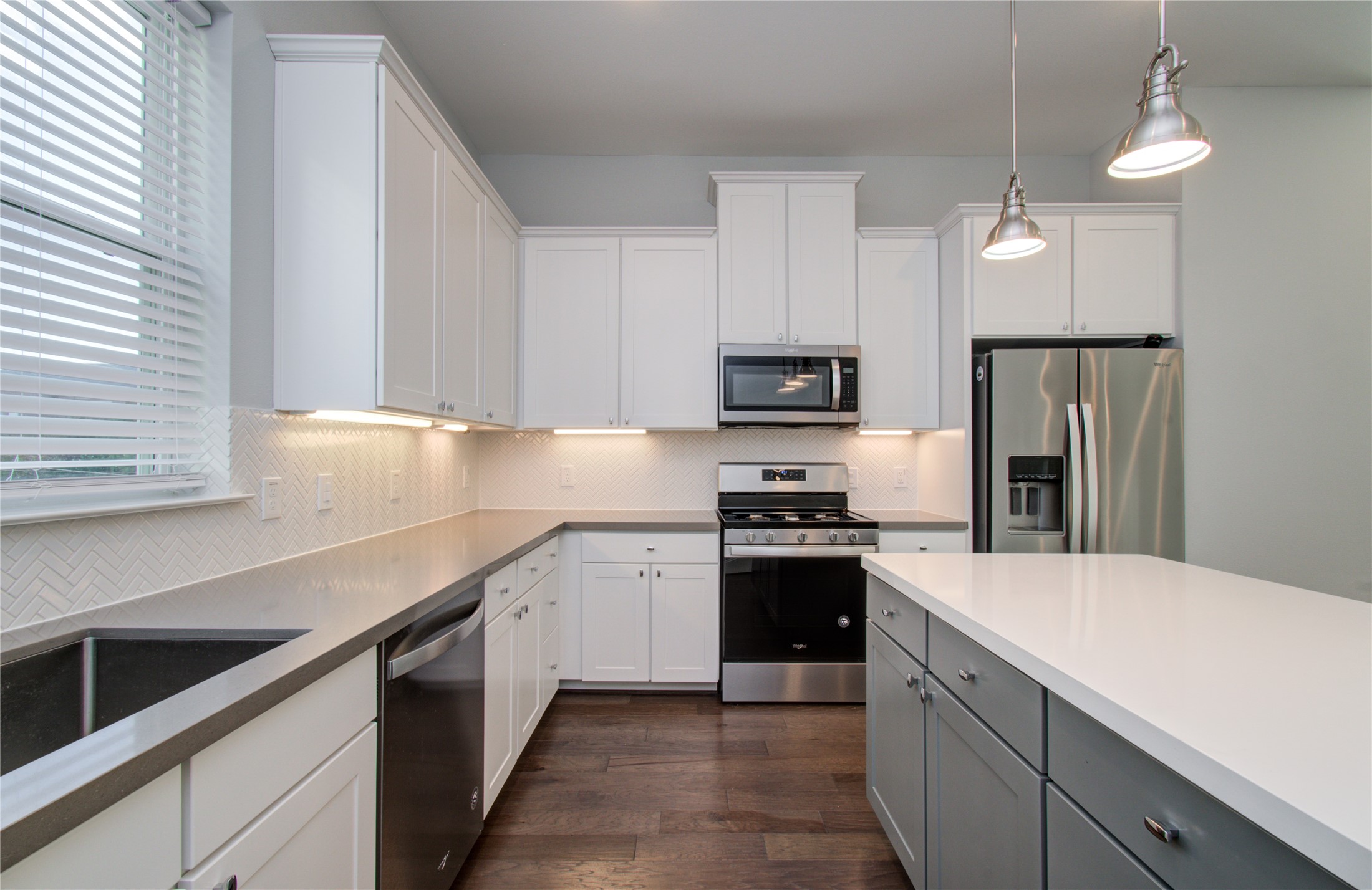 1262 North Post Oak Road, Unit A Houston, TX 77055 - Photo 21 of 50 A closer perspective of the kitchen showcases the combination of white upper and lower cabinetry paired with dark gray countertops. The central kitchen island features a contrasting sage-gray base and a thick white top.